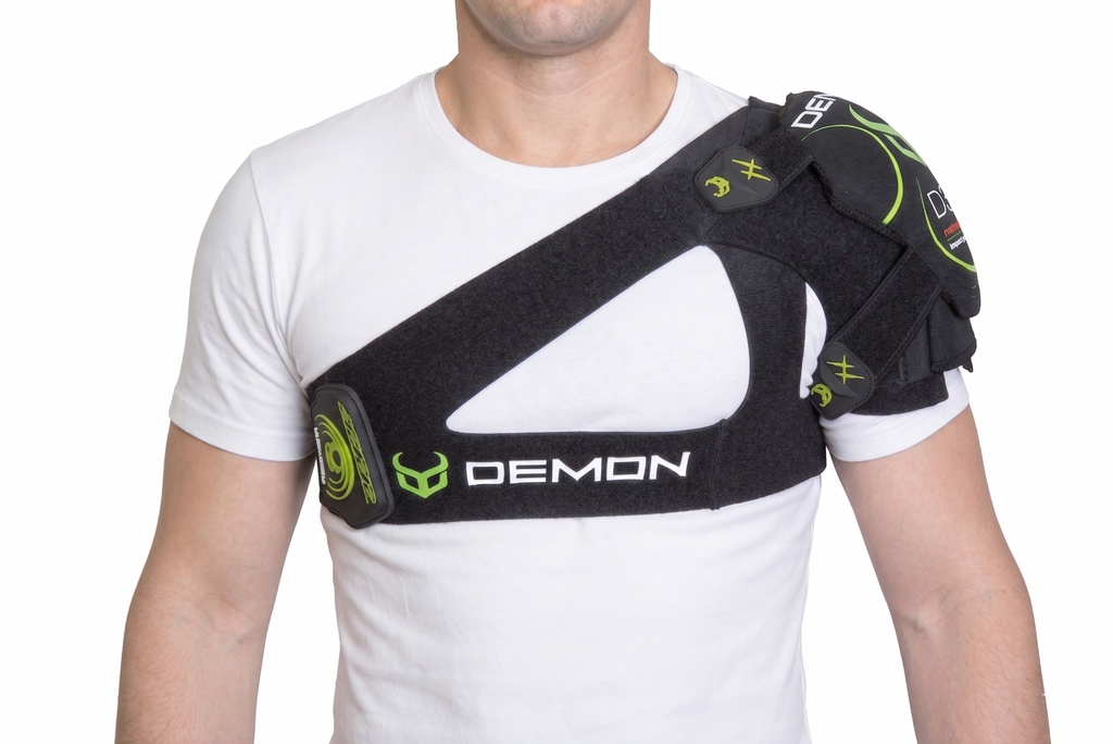 Person wearing a black shoulder brace with green accents on a white background