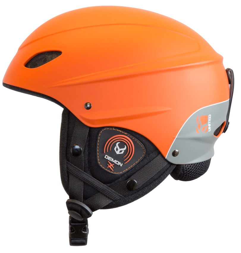 orange hardshell design with black ear pads with a white and orange demon logo, a black goggle strap clip, and adjustable chin strap. 