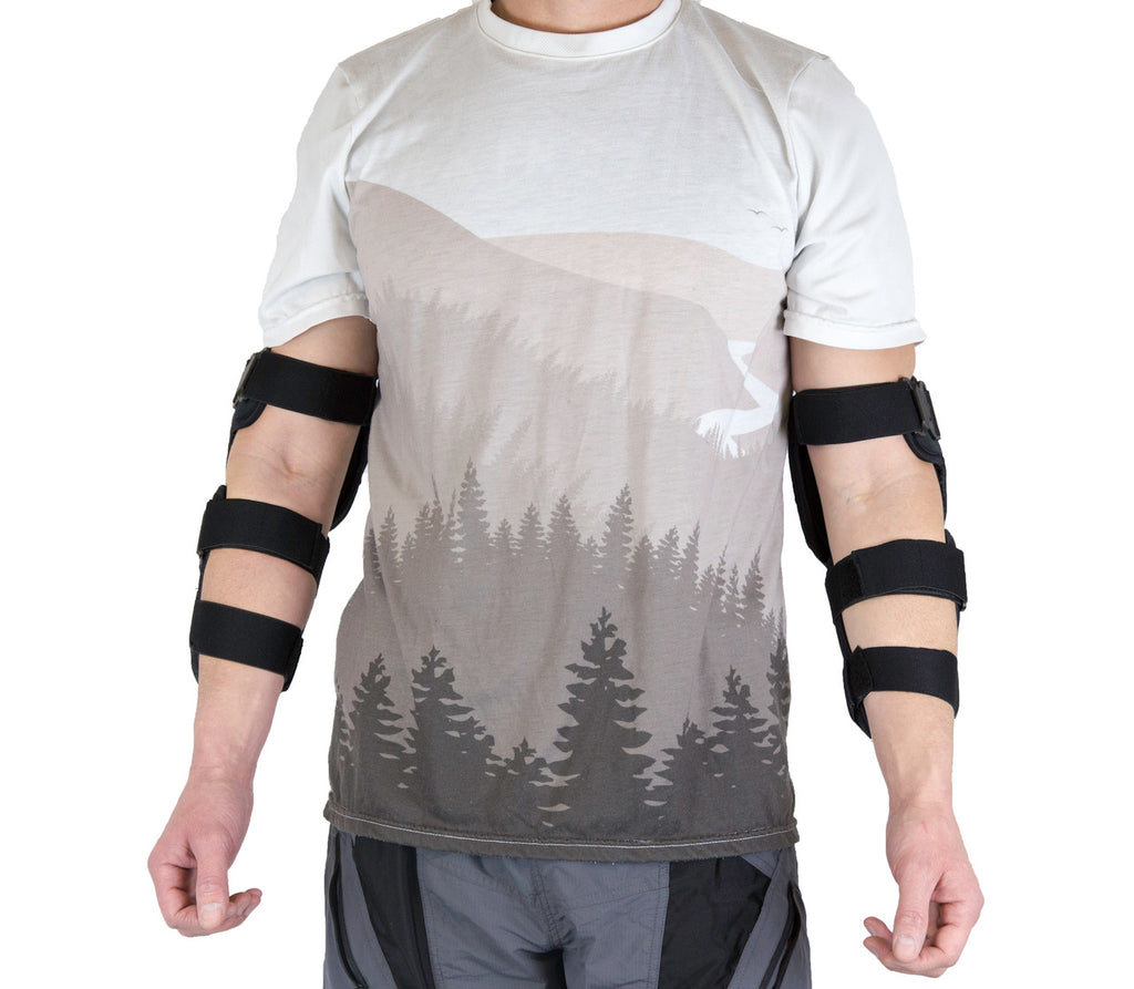Front view of a pair of black Demon hard-shell elbow and forearm guards being worn over a white shirt, featuring a dual-plate design and adjustable straps for heavy-duty joint and limb protection.
